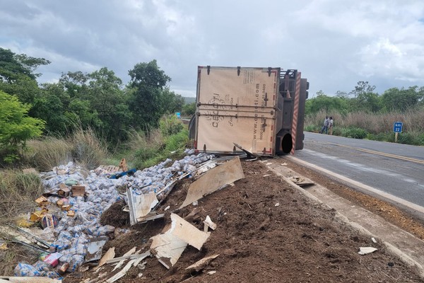 Caminhão baú com 11 toneladas de feijão tomba na MG 410 e parte da carga se espalha fora da pista