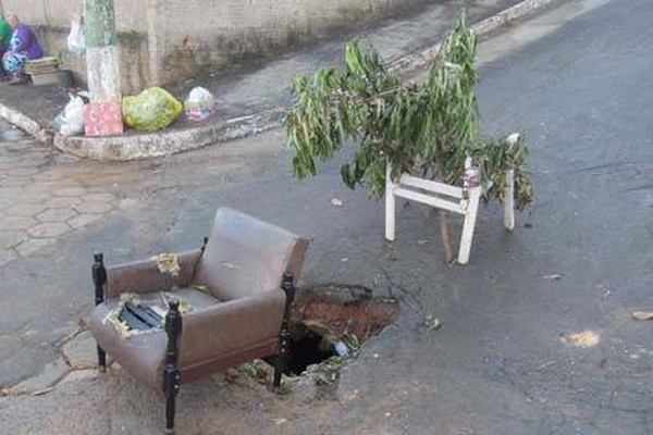 Moradores usam galhos de árvores, cadeira e até sofá para sinalizar buraco no centro