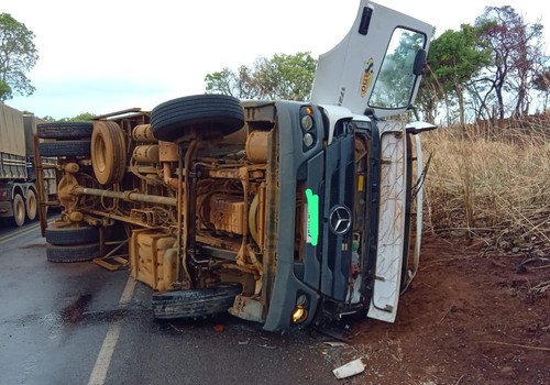 Motorista e passageiro ficam feridos após caminhão deslizar em pista molhada e tombar, na BR352