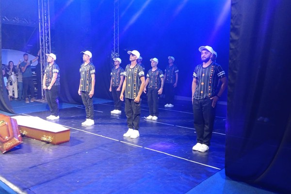 Os figurinos impressionam com chapéus, cadeiras e até caixão no palco; veja ao vivo